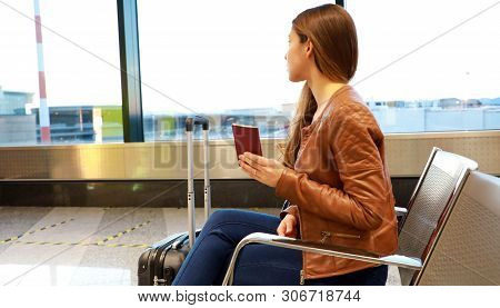 Beautiful Young Woman Looking Out Window While Waiting Boarding On Aircraft With Passport In Her Han
