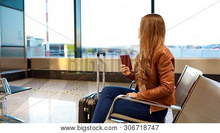 Beautiful Young Woman Looking Out Window While Waiting Boarding On Aircraft With Passport In Her Han