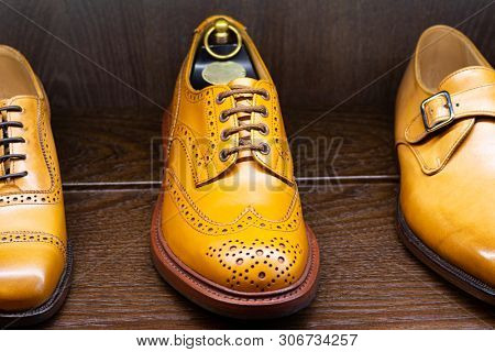 Tan full grain leather brogues shoes set on wooden display in in men shoes boutique store.