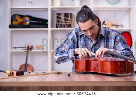 Young handsome repairman repairing cello