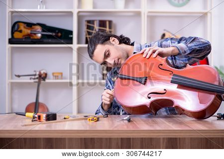 Young handsome repairman repairing cello