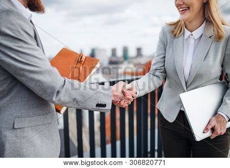 Midsection Of Young Business People Standing On A Terrace Outside, Shaking Hands.
