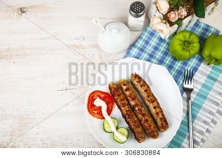 Kupaty In A White Plate And Vegetables On A Wooden Table. Sausages Grill. Tasty Food.