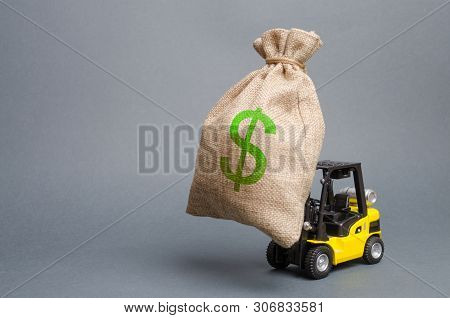 Yellow Forklift Truck Carries A Big Bag Of Money. Attracting Investment In The Development And Moder