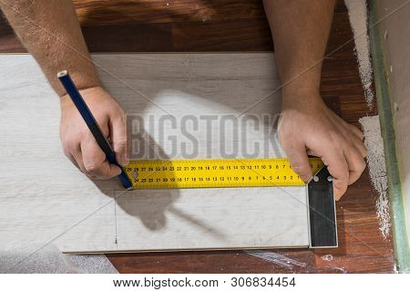Construcion Worker Measuring Floor Panels Using Ruler And Pencil. Home Renovation Concept.