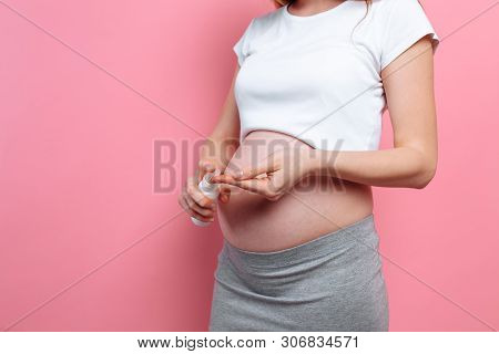 Pregnant Woman Applies Stretch Mark Cream On Her Belly, Moisturizing Her Skin