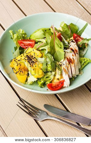 Salad With Grilled Chicken, Mango, Lettuce, Avocado, Tomatoes, Arugula, Cheese Sause On A White Plat