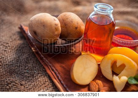 Glowing Face Mask Of Potato Juice In A Glass Bowl On Brown Colored Surface Along With Some Potato Ju