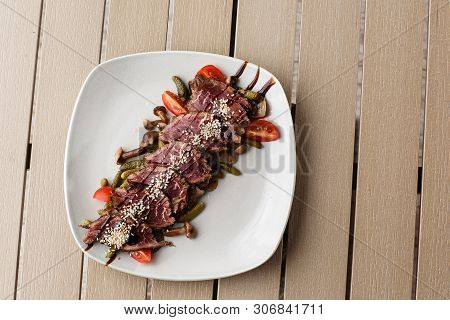 Sliced Medium Rare Roast Beef With Pickles, Cherry Tomatoes, Mushrooms On A White Plate On Wooden Ba