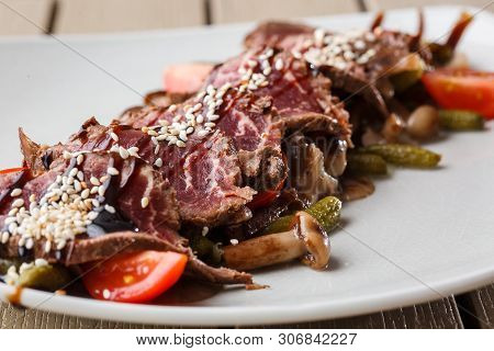 Sliced Medium Rare Roast Beef With Pickles, Cherry Tomatoes, Mushrooms On A White Plate On Wooden Ba