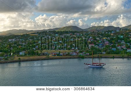 Foreboding Image Of A Single Sailboat Moored In St John`s Harbour, Antigua With Colourful Caribbean 