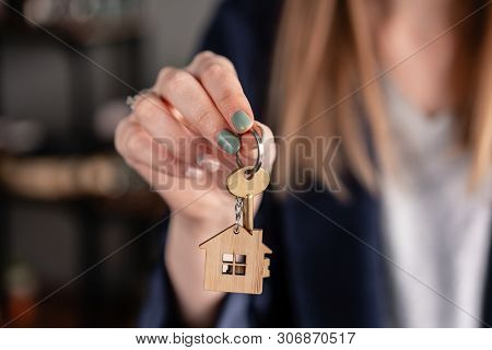 Concept Of Renting An Apartment. House Key In Womans Hands. Young Woman. Modern Light Lobby Interior