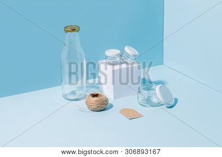 Composition Of Glass Jars On Pedestal, Empty Milk Bottle, Hank Of Twine And Blank Tag In The Corner 