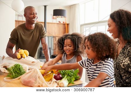 Family Returning Home From Shopping Trip Unpacking Plastic Free Grocery Bags