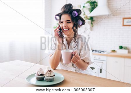 Attractve Beautiful Female Housewife Talking On Phone. Holding Cup In Hand. Pancakes On Plate. Gossi