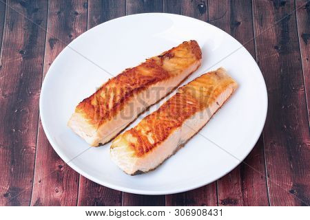 2 Grilled Salmon Steaks On White Plate Served On Wood.