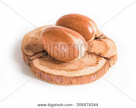 Moroccan Argan Nuts On Wood Background Close-up Isolated White. Argania Spinosa Seeds.