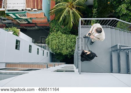 Business Colleagues Standing On Fire Escape Staircase, Talking And Looking At City, View From The To