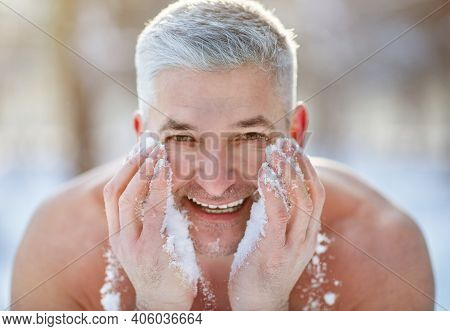 Happy Senior Man Washing His Face With Snow, Developing Resistance To Cold At Frosty Winter Park. Ch
