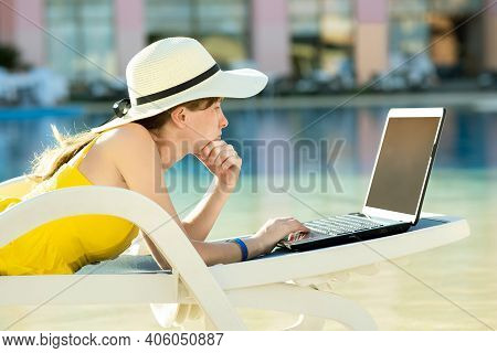 Young Woman On Beach Chair At Swimming Pool Working On Computer Laptop Connected To Wireless Interne