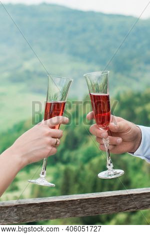 Glasses With Red Champagne Drink In Bride And Groom Hands. Happy Newlyweds Drinking. Loving Couple C