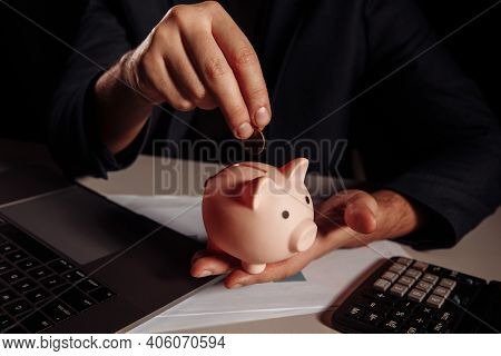 Man Putting Coin In Piggy Bank. Business And Investment Concept