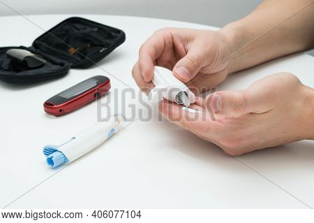 Closeup Of Young Man Using Lancelet On Finger In Bathroom
