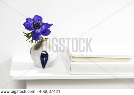 One Blue Anemone In A Multi-colored Vase In The Style Of The Seventies On The Table With Books As An