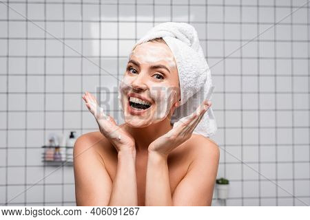 Excited Woman With Naked Shoulders Applying Foam Cleanser In Bathroom