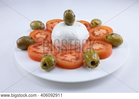 The Meal On A White Plate On A White Background Consists Of Sliced Tomatoes, Pitted Olives And Mozza