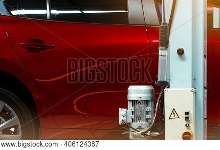 Selective Focus On Red Shiny Car And Pole Of Lift Machine With Motor And Motor Control Box In Auto R