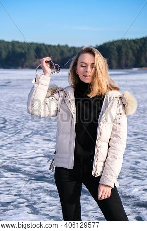 Young Female Smiling And Looking At A Camera In A Snow Landscape. Happy Hipster Girl With Hip Hop Wa