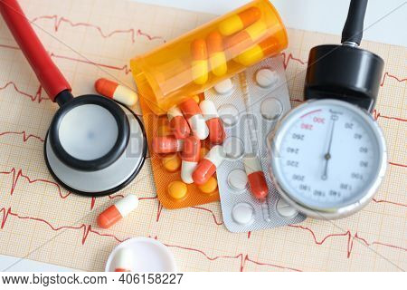 Tonometer And Blister With Pills Lying On Electrocardiogram. Diagnosis And Treatment Of Arterial Hyp
