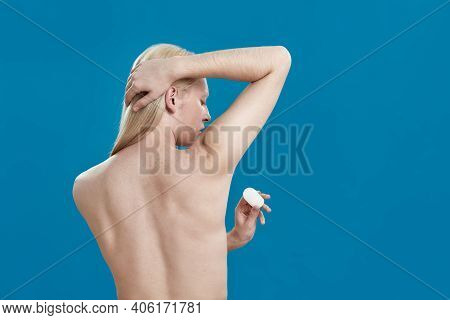 Young Caucasian Man With Long Fair Hair Using Crystal Deodorant On Armpit While Standing Backwards O