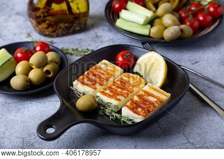 Grilled Haloumi Cheese On A Black Pan With Olives, Tomatoes, Cucumbers And Pepperoni. Close-up.