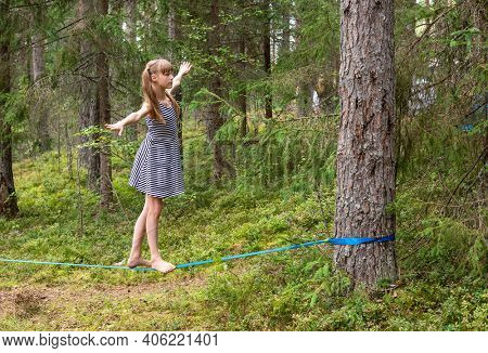 Tween girl balancing on slackline during summer holidays