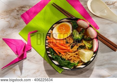 Spicy Korean Vegetable Ramen Garnished With Vegetables And A Soft Boiled Egg With Origami Crane Bird