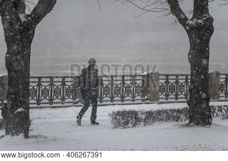 A Passer-by Walks Along The Embankment In A Heavy Snowfall. Snowfall In The City.