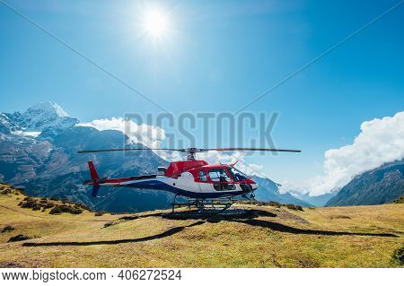 Civil Helicopter Landed In High Altitude Himalayas Mountains. Thamserku 6608m Mountain On The Backgr