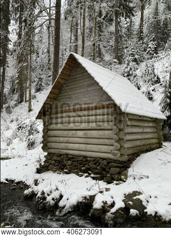 Wooden House In The Winter Forest. An Old Wooden Building. A Log House In The Middle Of A Snowy Fore