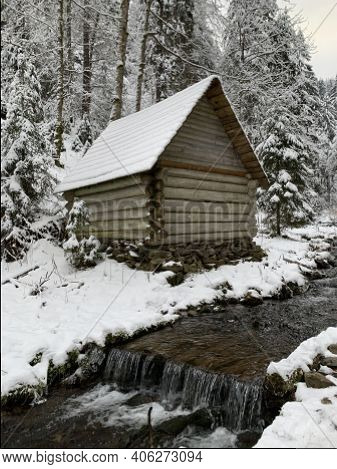 Wooden House In The Winter Forest. An Old Wooden Building. A Log House In The Middle Of A Snowy Fore