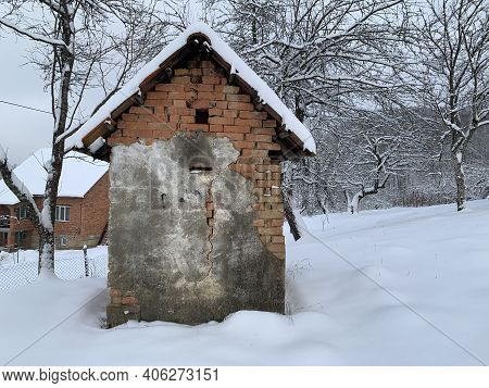Old Brick Shed In The Snow. Rural Building In The Yard. A Covered House Is A Utility Room.
