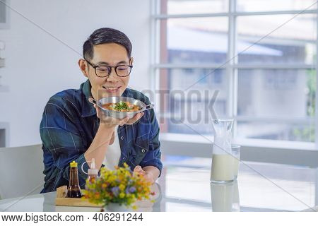 Young Man's Wearing Glasses Sitting And Looking At The Fried Egg Served On A Pan With Colorful Toppi