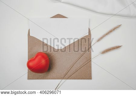 Blank White Paper Is Placed On Open Brown Paper Envelope With Red Heart, Bristly Foxtail Dry Flower,