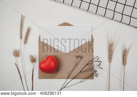 Blank White Paper Is Placed On Open Brown Paper Envelope With Red Heart, Many Kinds Of Dried Flowers