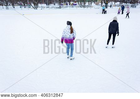 Close-up Of Girls Ice Skating In Winter On An Outdoor Ice Rink. Ice Skates Of Two Friends Ice Skatin