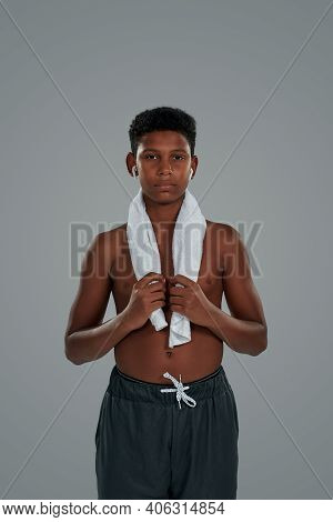 Resting After Workout. Halfnaked Teenage African Boy With Towel On Shoulders Wearing Wireless Earpho