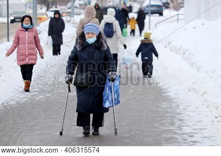 Moscow, Russia - February 2021: Elderly Woman In Medical Mask Walking With A Canes And Bag On A City