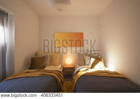 Modern bedroom with two singles beds with clean bed sheets and large pillow above. White wall. Nobody inside.