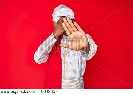 Handsome indian man wearing tradition sherwani saree clothes covering eyes with hands and doing stop gesture with sad and fear expression. embarrassed and negative concept. 